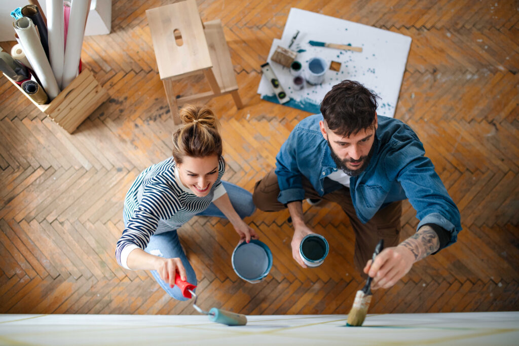 Young couple painting wall.  Fresh paint is one of the best ways to increase your home's value.